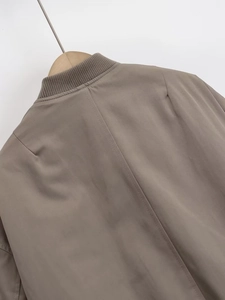 Detalle de chaqueta bomber caqui mostrando el cuello acanalado y costura trasera central