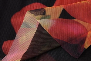 Macro shot of breathable black mesh fabric with vibrant red and orange floral prints