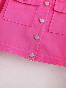 Détail de la veste tissée rose vif avec boutons argentés et grandes poches plaquées