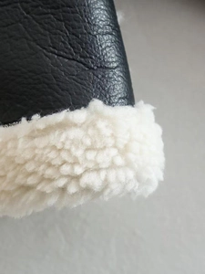Detailed close-up of black pebble leather and soft white faux shearling lining on jacket