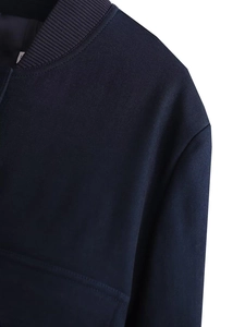 Macro detail of navy blue jacket showing ribbed collar and twill fabric texture