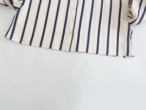 Detail of pinstripe shirt featuring pearl-like buttons and smooth woven fabric texture
