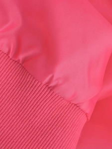 Close-up of vibrant pink Y2K bomber jacket fabric showing ribbed cuffs and smooth texture