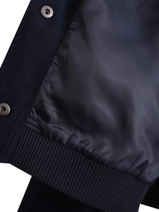 Close-up of navy bomber jacket with metallic star snap button and ribbed hem texture