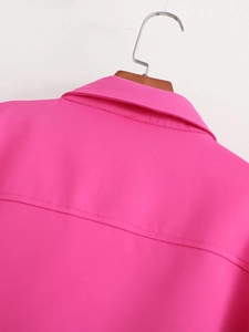 Détail du col de chemise rose et des coutures du dos sur un cintre en bois