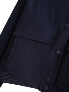 Detail of dark blue bomber jacket featuring a large flap pocket and matte snap buttons