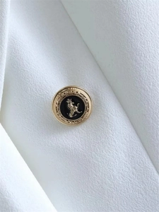 Close-up of golden lion crest metal button with black enamel on white tweed fabric