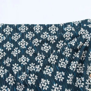 Detailed view of teal floral skirt featuring beaded hem and side knot drapery detail