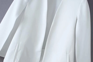 Detailed view of white blazer jacket with smooth fabric texture and slit pocket design