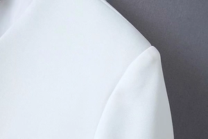 Detailed close-up of white blazer shoulder seam with premium textured woven fabric