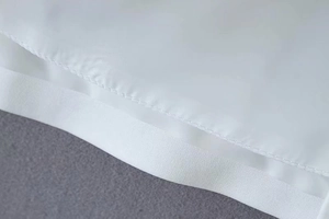 Detailed close-up of white blazer cape showing neat single-needle stitching and fabric texture