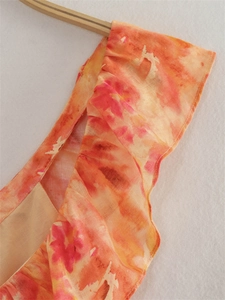 Dettaglio del vestito midi Y2K tie-dye con tessuto in lino arancione e spalline a balze