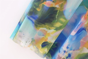 Close-up of semi-transparent floral chiffon fabric with abstract blue and orange patterns