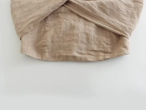 Vue détaillée de la texture en lin naturel et du design croisé asymétrique à la taille