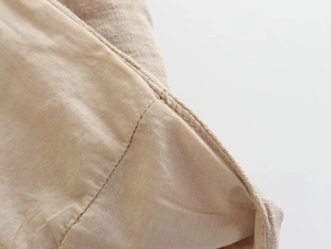 Gros plan sur la texture du lin beige et les coutures fines du pantalon d'été à taille haute