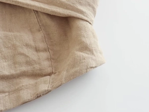 Gros plan sur le tissu en lin beige montrant la texture tissée et les détails de couture
