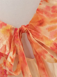 Dettaglio dello scollo in lino con fiocco decorativo e vivace stampa floreale ad acquerello