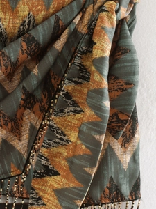 Detailed close-up of geometric print fabric with intricate beaded fringe on the hem