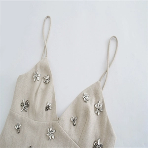 Dettaglio della canotta beige con scollo a V e raffinati fiori di strass applicati