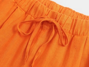 Détail du pantalon en lin orange montrant la taille élastique et le nœud du cordon