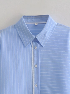 Detail of light blue striped shirt featuring a sharp collar and contrasting button placket