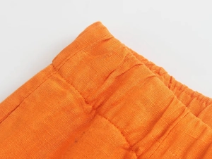 Détail de la taille élastique d'un pantalon en lin orange avec texture de tissu