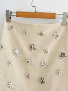 Close-up of beige Y2K mini skirt showing intricate floral rhinestone beads and fabric texture