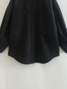 Detailed shot of heavy black jacket with front utility pockets and curved hemline