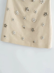 Detail of sequined flower beads on a beige Y2K mini skirt with high-end linen texture