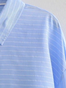 Detail of light blue striped shirt collar and shoulder stitching with fine cotton texture