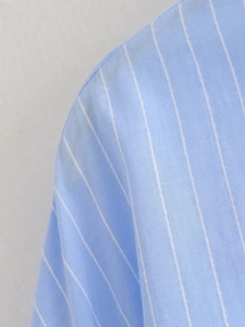 Macro detail showing blue and white striped twill fabric texture on a summer shirt