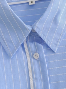 Detailed view of striped shirt collar with white buttons and S size label