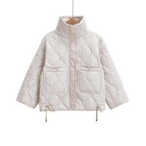 Close-up of cream quilted jacket featuring onion stitching, large pockets and drawstring hem