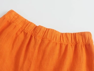 Détail du pantalon en lin orange vif montrant la taille élastique et la texture du tissu
