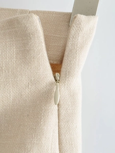 Detailed close-up of invisible zipper and textured oat-colored woven fabric on skirt