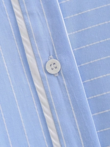 Detailed macro view of white button and blue striped cotton fabric on Y2K summer set