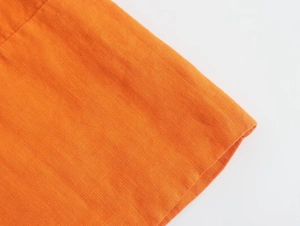Détail macro du tissu en lin orange vif montrant les coutures et la texture tissée
