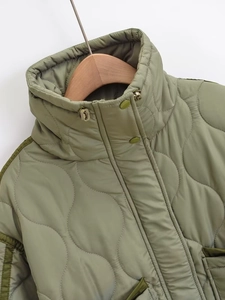 Detail of high stand collar and wavy quilted texture on olive green puffer jacket