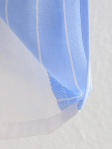 Close-up of light blue and white striped cotton fabric with neat edge stitching details