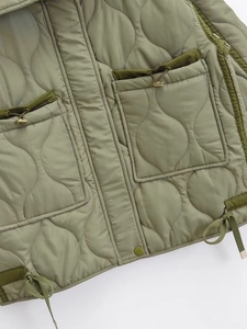 Detail of sage green quilted jacket featuring onion stitching and large drawstring pockets