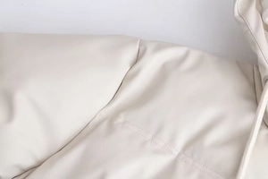 Détail de la veste à capuche en cuir PU blanc crème avec coutures fines et cordons tressés