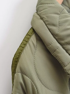 Close-up of olive green quilted jacket featuring meticulous onion stitch and binding