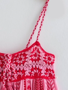 Detail of pink crochet knit top with floral cutouts and bohemian tassel accents