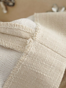 Detail of beige woven fabric texture showing fine white stitching and mesh lining