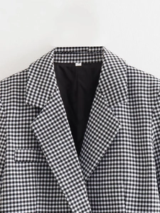 Détail du revers d'un blazer à motif pied-de-poule noir et blanc avec étiquette S