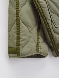 Detail of olive green quilted jacket featuring onion stitch pattern and bound edges