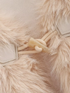 Détail d'un gilet en fausse fourrure beige avec fermeture par bouton bascule en corne