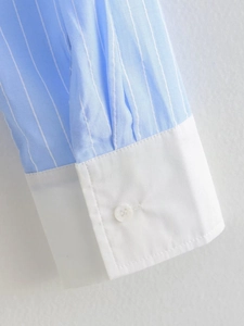 Detail shot of blue and white striped shirt cuff with white button and neat stitching