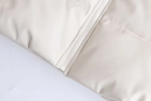 Détails de la fermeture éclair et des surpiqûres de la veste matelassée beige crème