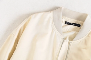 Détail du col côtelé et de l'étiquette de marque d'un blouson aviateur crème style Y2K